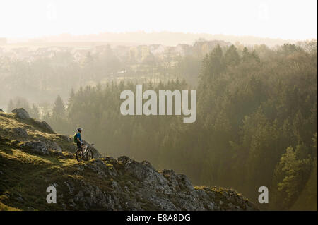 Junger Mann Mountainbiken bei Sonnenaufgang, Bayern, Deutschland Stockfoto