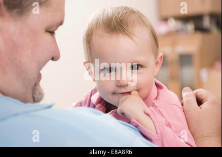 Vater hielt Babymädchen in seinen Armen lächelnd Stockfoto