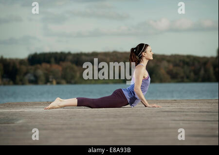 Frau praktizieren Yoga auf Steg, Woerthsee, Bayern, Deutschland Stockfoto