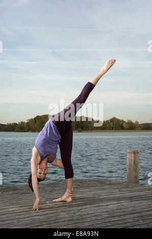 Frau praktizieren Yoga auf Steg, Woerthsee, Bayern, Deutschland Stockfoto