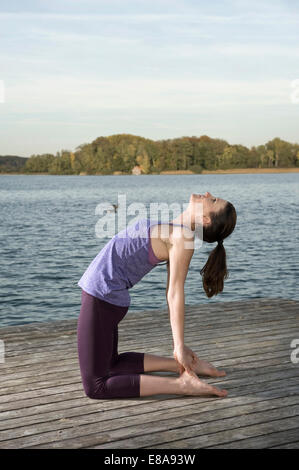 Frau praktizieren Yoga auf Steg, Woerthsee, Bayern, Deutschland Stockfoto