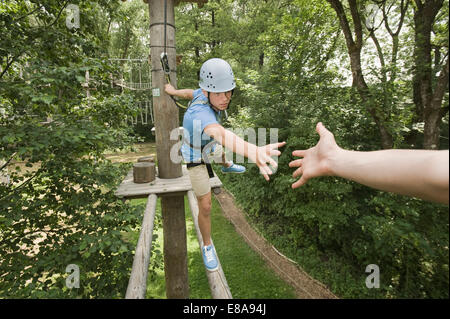 Teenager in einem Klettergarten hilft einem anderen Stockfoto