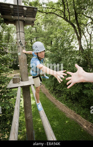 Teenager in einem Klettergarten hilft einem anderen Stockfoto