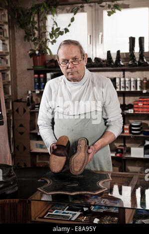 Schuster im Speicher halten Paar Lederschuhe Stockfoto