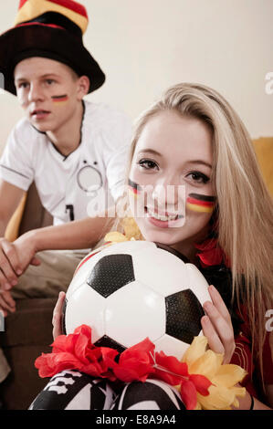 Teenager-Jungen und Mädchen mit Fußball im Wohnzimmer Stockfoto