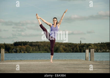 Frau praktizieren Yoga auf Steg, Woerthsee, Bayern, Deutschland Stockfoto