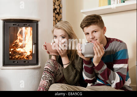 Teenager-paar trinken von heißen Getränken vor Kamin Stockfoto