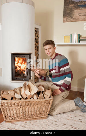 Teenager mit Protokoll vor der Kamin Stockfoto