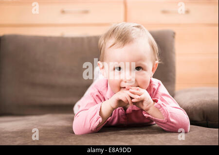 Babymädchen 18 Monate liegen auf Sofa-Porträt Stockfoto