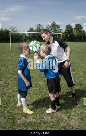 Fußball-Trainer hilft jungen Fußballer Stockfoto