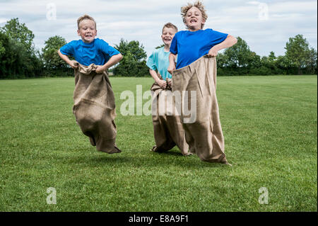 Drei junge Burschen läuft in Sackrace springen Stockfoto