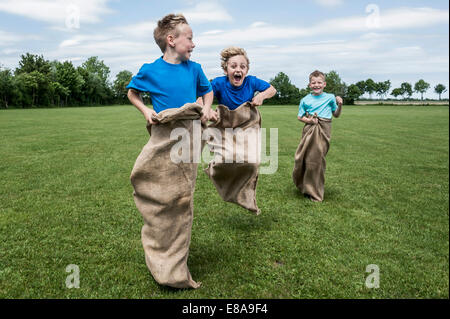 Drei junge Burschen läuft in Sackrace springen Stockfoto