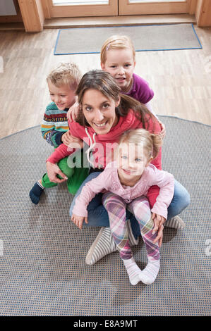 Gruppenbild der weiblichen Erzieher und drei Kinder sitzen am Boden im kindergarten Stockfoto