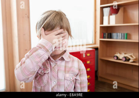 Kleines Mädchen, die ihre Augen mit der Hand bedecken Stockfoto