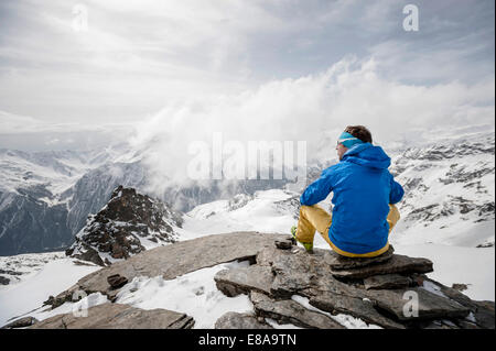 Mann, sitzend Betrachtung Mountain Peak winter Stockfoto