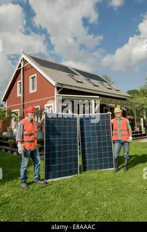 Zwei Arbeiter halten Solarpanel Garten Stockfoto