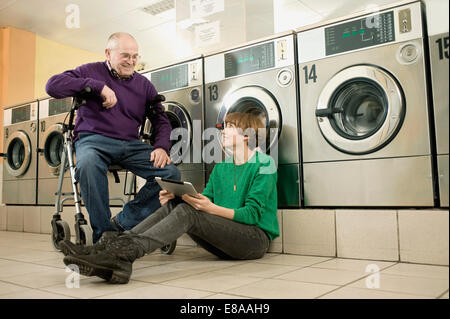 Mann und Frau sprechen in Wäscherei, Lächeln Stockfoto