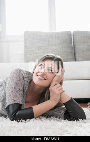 Porträt der glückliche junge Frau auf Teppich zu Hause entspannen Stockfoto