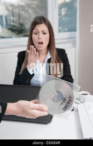 Hand, die CD, junge entsetzt Geschäftsfrau sitzen im Hintergrund Stockfoto
