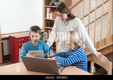 Zwei jungen und weiblichen Kinderpflegerin mit Laptop und Tablet-computer Stockfoto