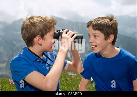 Zwei Jungs im Teenageralter halten Ferngläser in Alpen Stockfoto