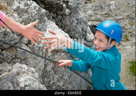 Hand hilft jungen Klettern Alpen erreichen Stockfoto
