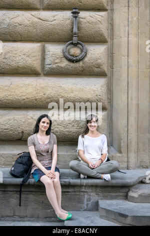 zwei junge ziemlich europäischen Besucher Florenz entspannen demurely in der Piazza di San Firenze an der Basis eines alten Gebäudes Stockfoto