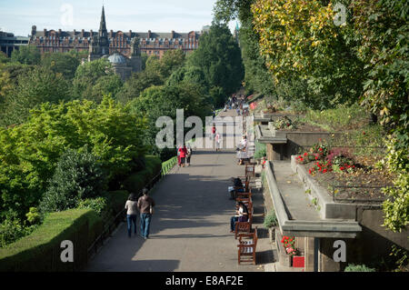 Menschen zu Fuß durch die Princes Street Gardens, Edinburgh. Das Caledonian Hotel im Hintergrund. Stockfoto