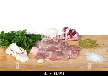Hühnerfleisch liegt auf Schneidebrett mit Pilzen, Knoblauch, Dill, Petersilie, Salz, Würze Stockfoto
