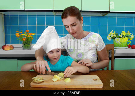 Mutter lehrt Tochter, schneiden Sie die Kartoffeln in der Küche Stockfoto