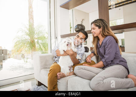 Paar Petting niedlichen Hund auf Wohnzimmer-sofa Stockfoto