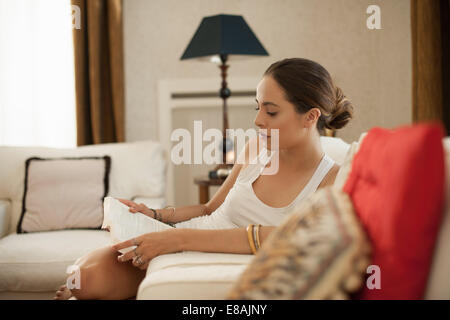 Junge Frau Buch auf Wohnzimmer-sofa Stockfoto