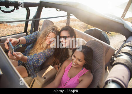 Drei junge Frauen, die die Selfie auf Smartphone im Jeep an Küste, Malibu, Kalifornien, USA Stockfoto