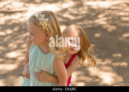 Junges Mädchen versteckt sich hinter Schwester im park Stockfoto