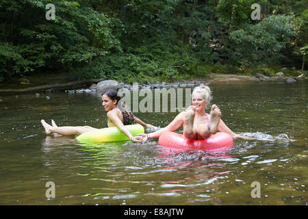 Frauen im Fluss mit aufblasbaren Ringen Stockfoto