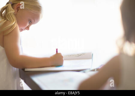 Zwei Schwestern, die in Büchern mit Buntstiften färben Stockfoto