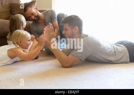 Männlichen Partner und zwei Töchter spielen Spiel Erdgeschoss Wohnzimmer klatschte Stockfoto