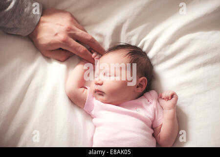 Babymädchen schläft, Hände von Vater Stockfoto