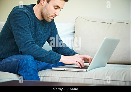 Mann mit Laptop auf dem Sofa Stockfoto