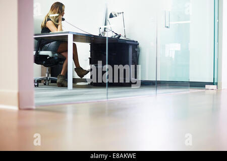 Junge Frau am Telefon im Büro Stockfoto