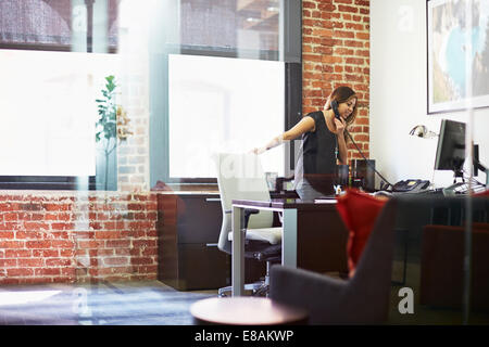 Junge Frau mit Telefon im Büro Stockfoto