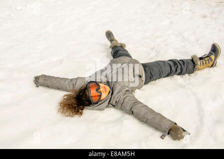 Mädchen auf dem Rücken im Schnee liegend Stockfoto