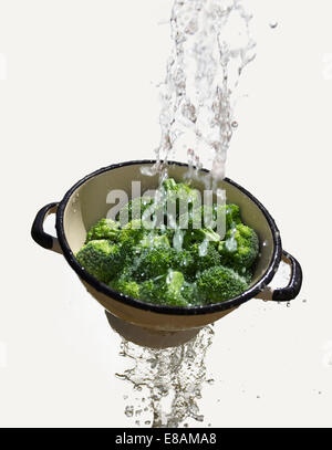 Wasser fällt durch das Sieb mit frischem Brokkoli Stockfoto