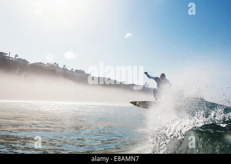 Mitte erwachsenen männlichen Surfer springen über Welle, Leucadia, Kalifornien, USA Stockfoto