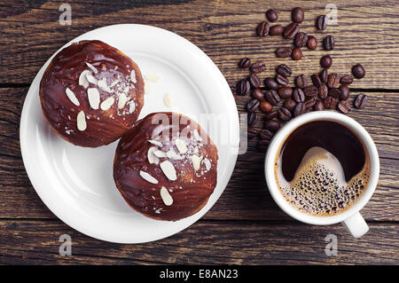 Tasse heißen Kaffee und Kuchen mit Schokolade und Nüssen auf Holztisch Stockfoto