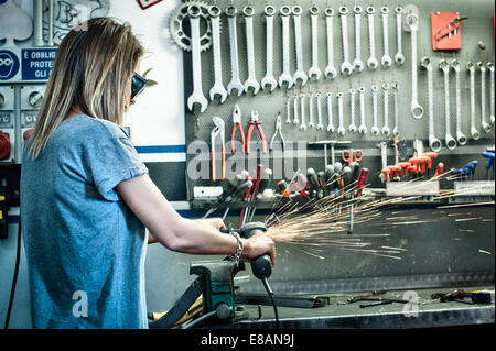 Weibliche Mechaniker Schleifen Metall im workshop Stockfoto