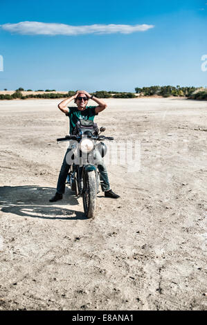 Mitte erwachsenen Mann sitzt auf dem Motorrad auf trockenen Ebene, Cagliari, Sardinien, Italien Stockfoto