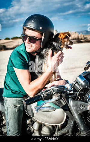 Mitte erwachsener Mann und Hundesitting auf Motorrad auf trockenen Ebene, Cagliari, Sardinien, Italien Stockfoto