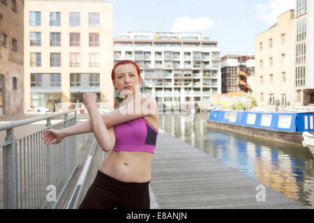 Frau tut Dehnübung, Gebäude im Hintergrund, East London, UK Stockfoto