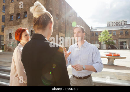 Drei junge Leute sprechen, Gebäude im Hintergrund, East London, UK Stockfoto